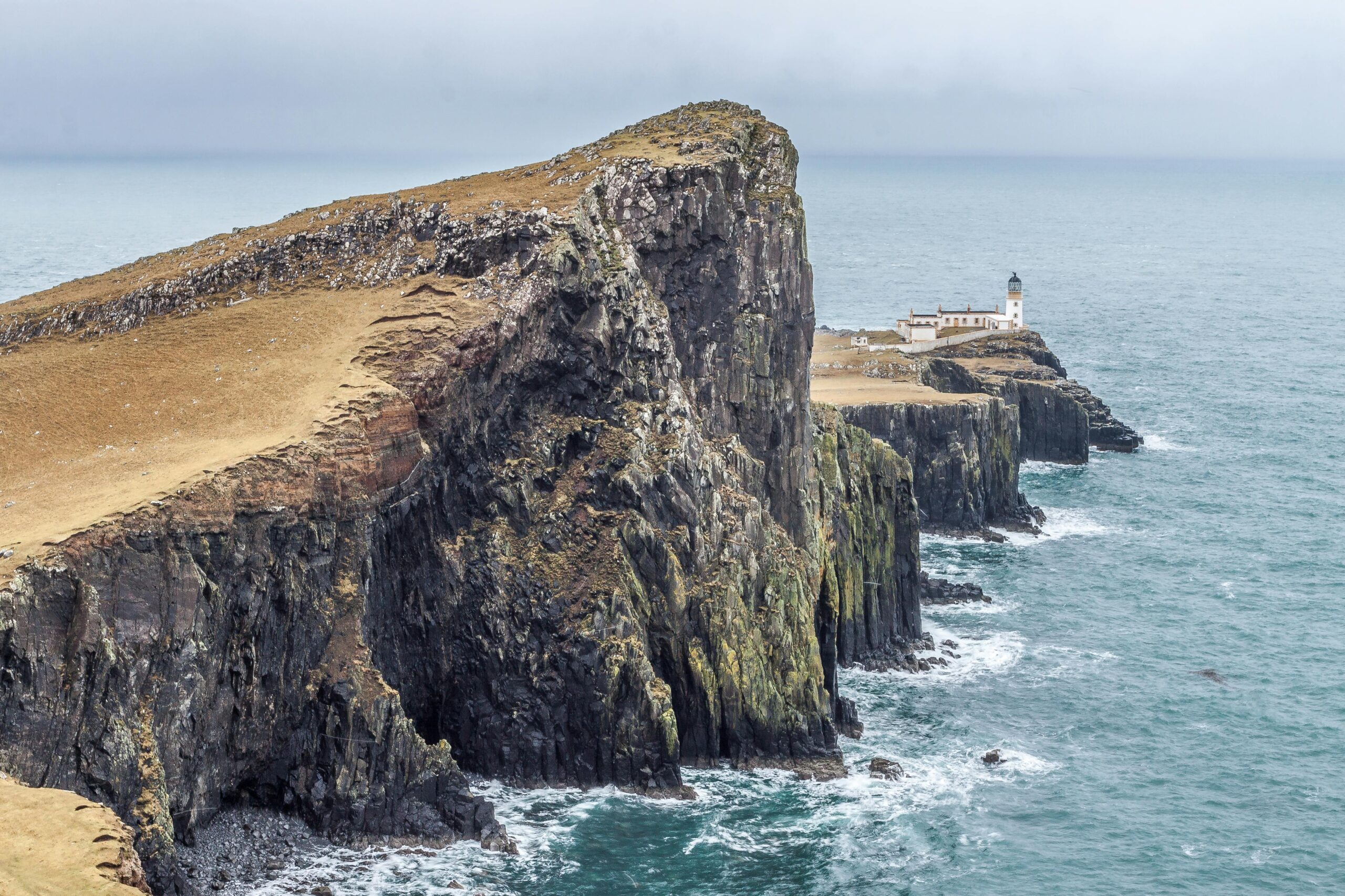 Dramatic cliffs and the iconic Neist Point Lighthouse on the captivating Isle of Skye coastline in Scotland.